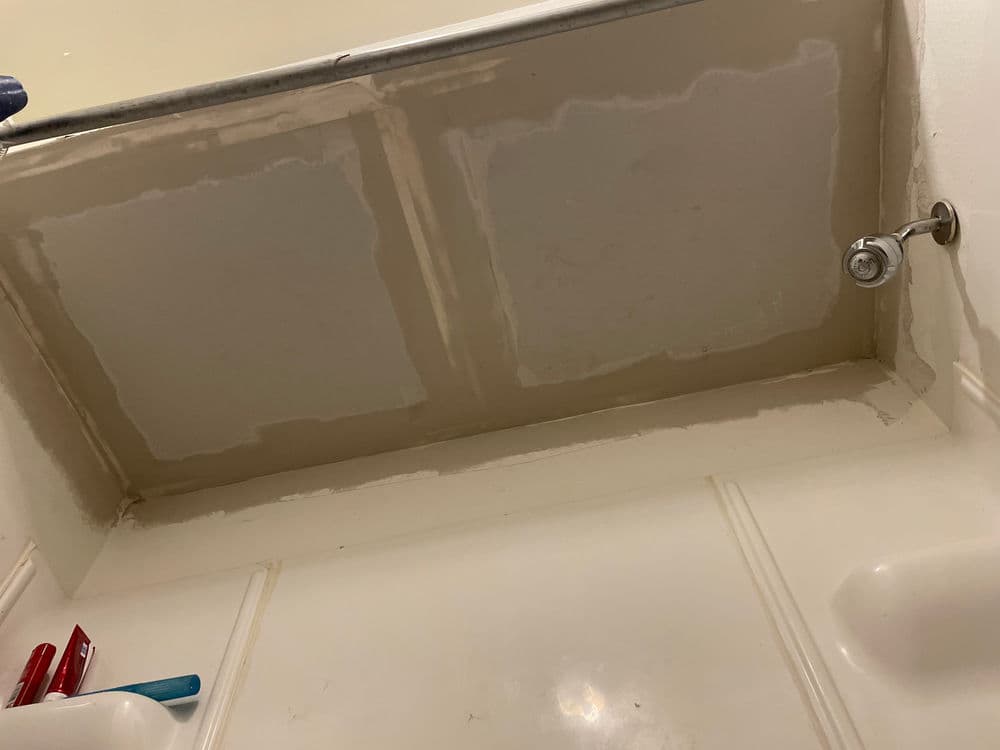 Bathroom ceiling with unfinished drywall and a faucet, viewed from below. Renovation progress.